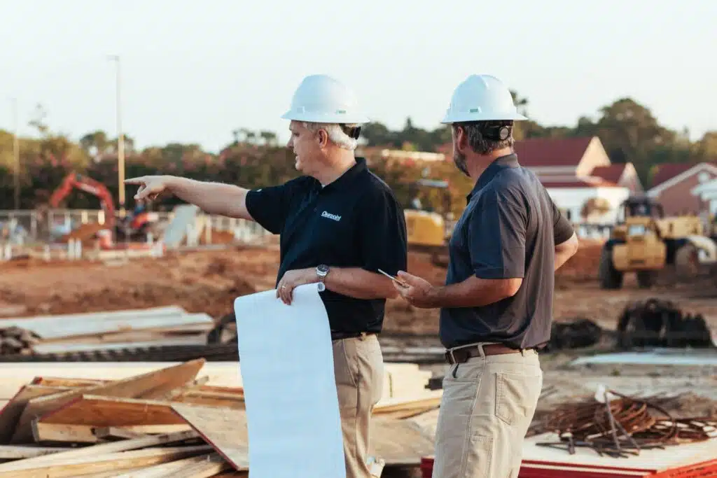 Two men at a worksite wearing hard hats