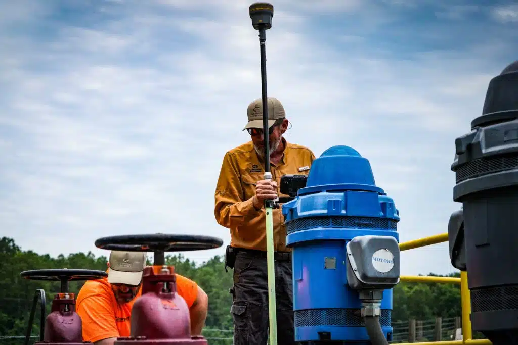 Workers operating machinery near lagoon