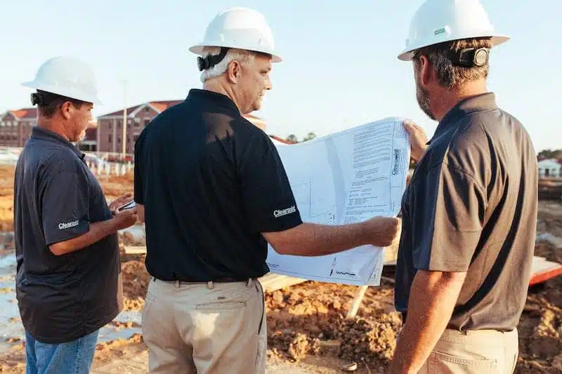 Construction workers reviewing blueprints outdoors.
